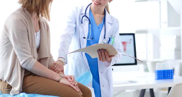 a patient sits on an exam table as a doctor goes over the plan of care