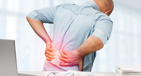 a man grabs his lower back in pain
