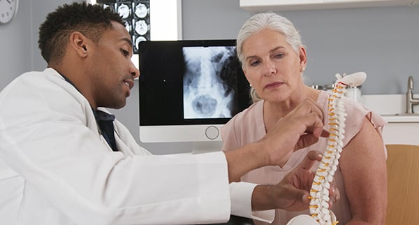 a doctor shows a patient a model of the spine